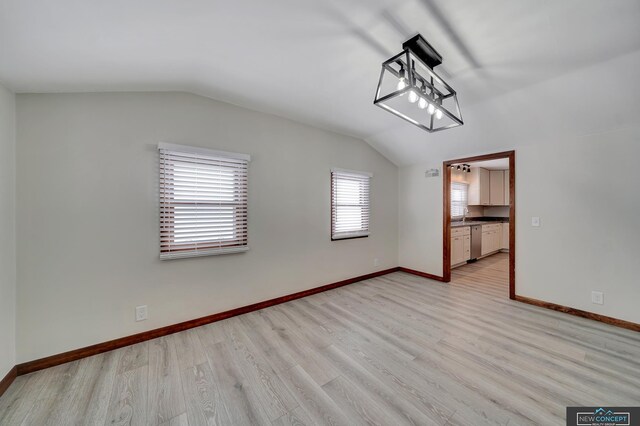 spare room featuring light hardwood / wood-style floors and lofted ceiling