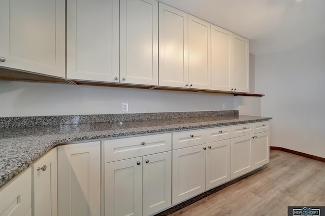 kitchen with white cabinetry, light stone countertops, and light hardwood / wood-style floors