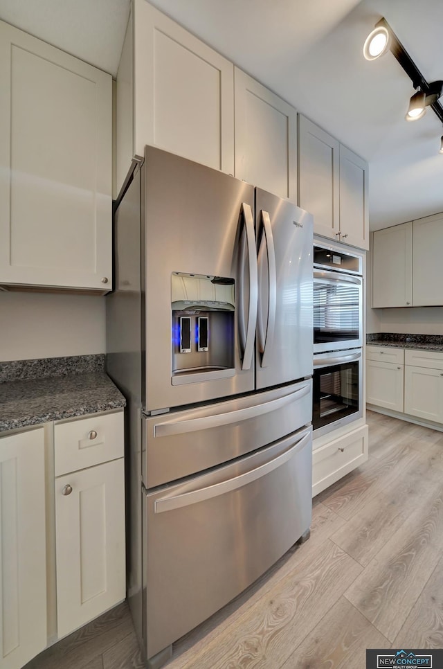 kitchen featuring light wood-type flooring, appliances with stainless steel finishes, and white cabinets