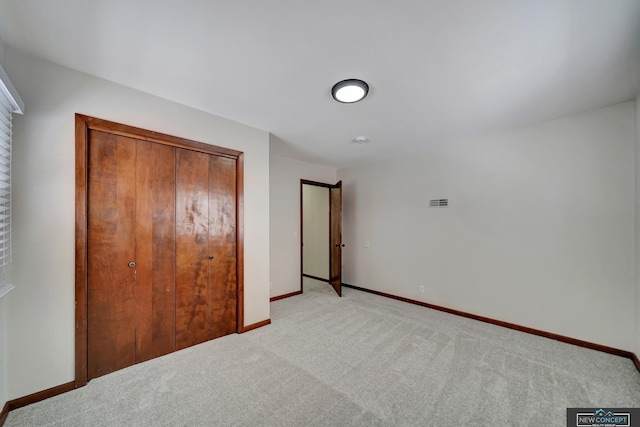 unfurnished bedroom featuring a closet and light colored carpet