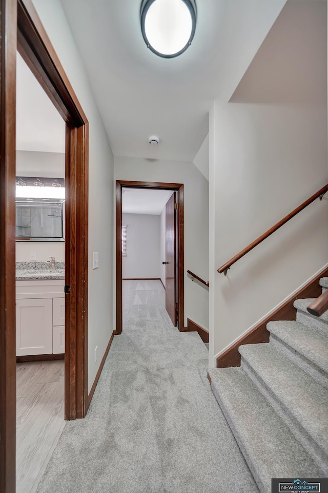 hall featuring light carpet and sink