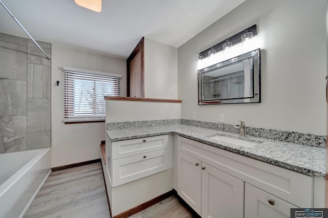 bathroom with vanity, tiled shower / bath, and hardwood / wood-style floors