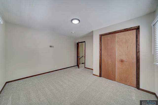 unfurnished bedroom with a closet and light colored carpet