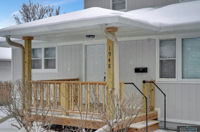 snow covered property entrance featuring covered porch