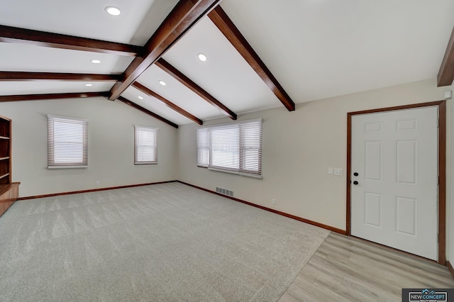 unfurnished living room with light hardwood / wood-style flooring, vaulted ceiling with beams, and a wealth of natural light