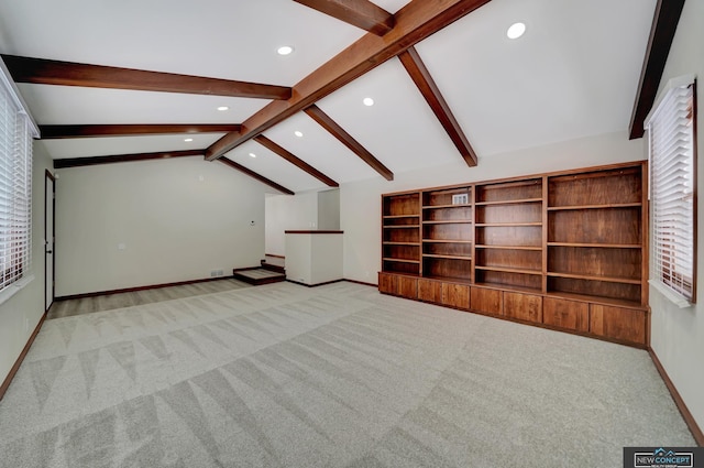 additional living space featuring light carpet, vaulted ceiling with beams, and plenty of natural light