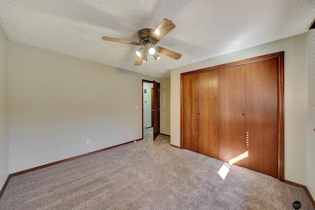 unfurnished bedroom with a closet, light colored carpet, a textured ceiling, and baseboards