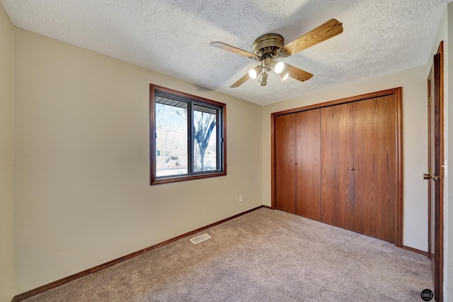 unfurnished bedroom featuring carpet, a closet, visible vents, a textured ceiling, and baseboards