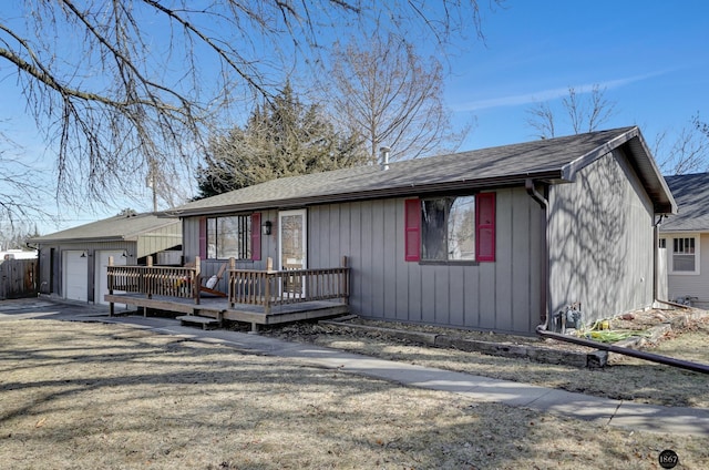 view of front of house with a garage, a shingled roof, a wooden deck, and fence