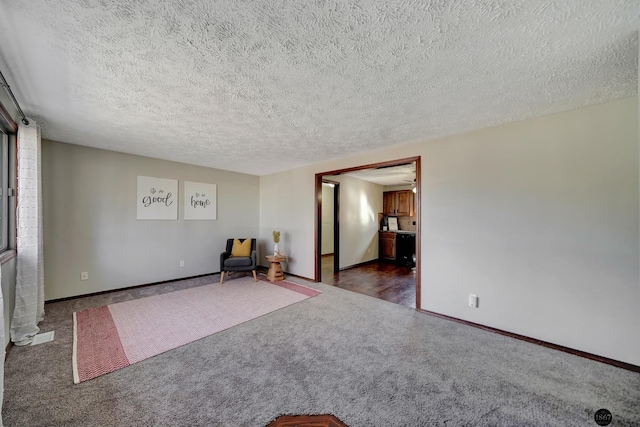 unfurnished room featuring dark carpet, a textured ceiling, and baseboards