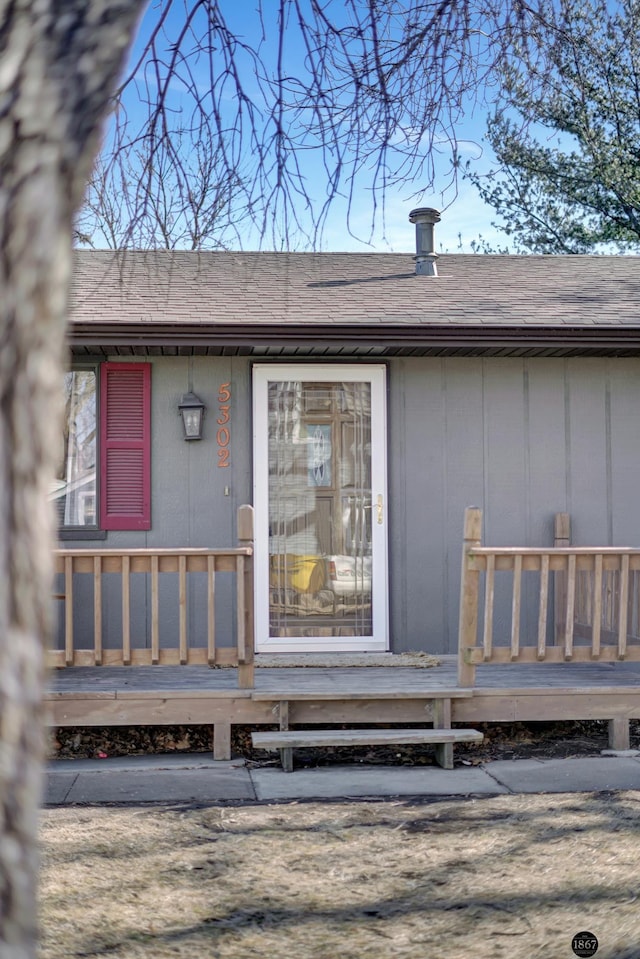 entrance to property featuring a shingled roof