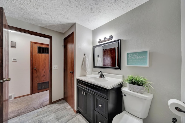 half bathroom with visible vents, a textured ceiling, toilet, and vanity