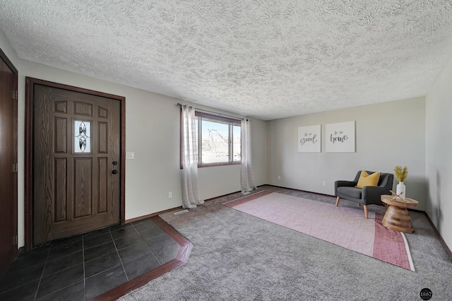 foyer with a textured ceiling, dark carpet, and baseboards