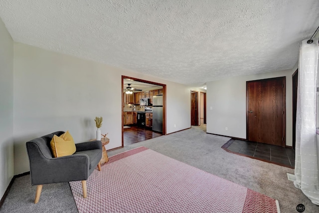 bedroom with ensuite bathroom, a textured ceiling, baseboards, freestanding refrigerator, and carpet