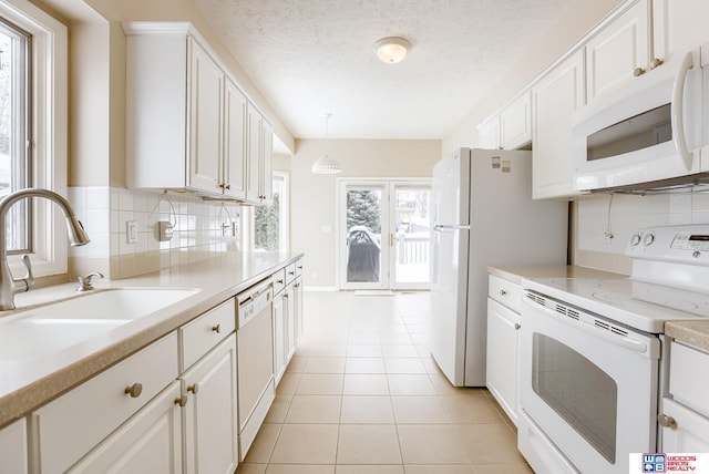 kitchen with white appliances, sink, light tile patterned flooring, pendant lighting, and white cabinets