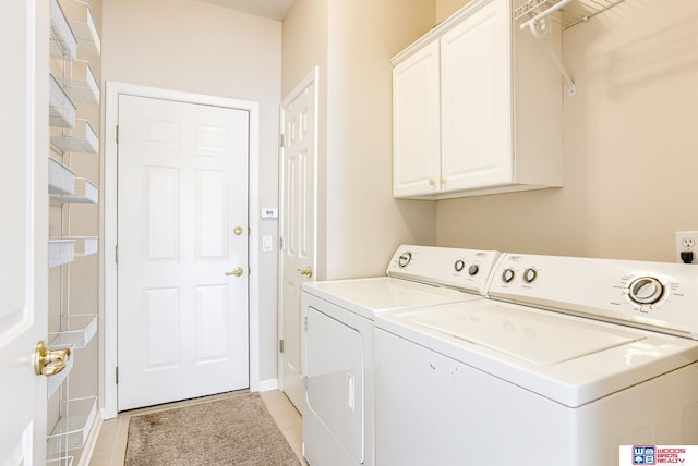 clothes washing area with light tile patterned flooring, washer and clothes dryer, and cabinets