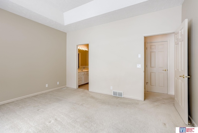 unfurnished bedroom featuring light carpet and connected bathroom