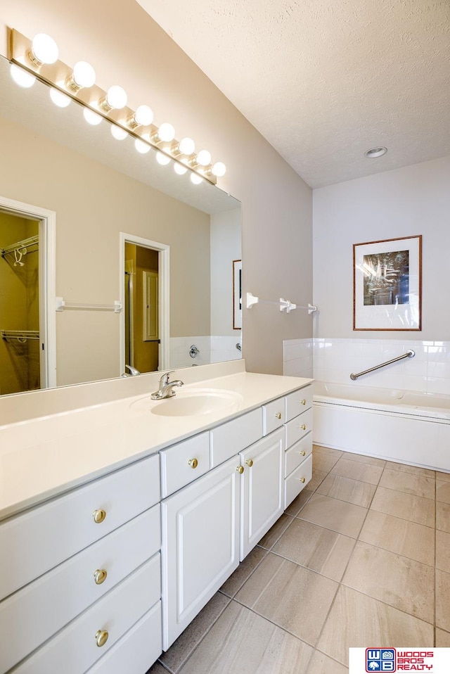 bathroom featuring a textured ceiling, tile patterned flooring, a bathtub, and vanity