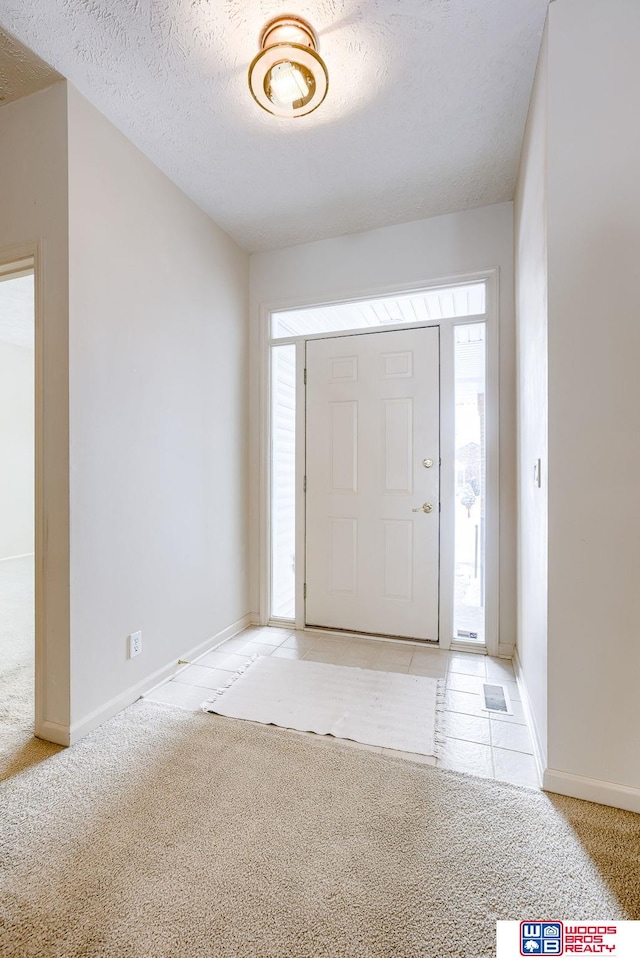 foyer featuring light carpet and a textured ceiling