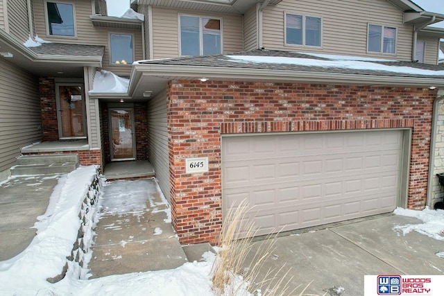 snow covered property entrance featuring a garage