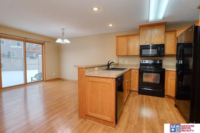 kitchen featuring sink, pendant lighting, light hardwood / wood-style floors, black appliances, and kitchen peninsula