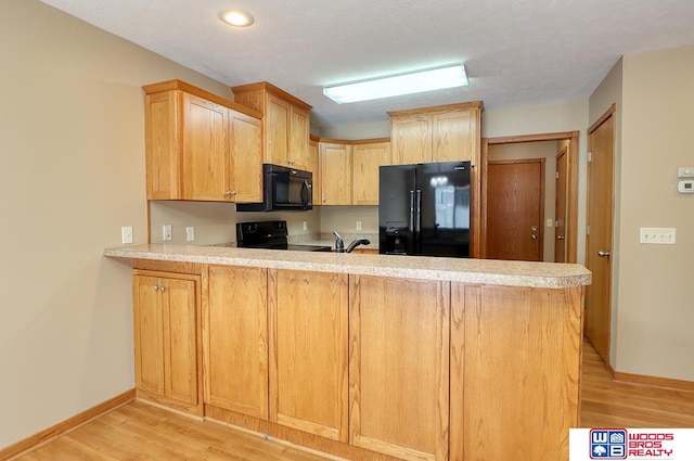 kitchen featuring kitchen peninsula, black appliances, light brown cabinets, and light hardwood / wood-style floors