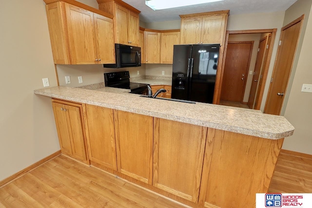 kitchen featuring sink, kitchen peninsula, black appliances, and light hardwood / wood-style floors