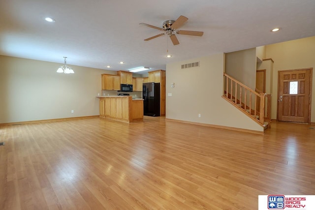 unfurnished living room featuring ceiling fan with notable chandelier and light wood-type flooring