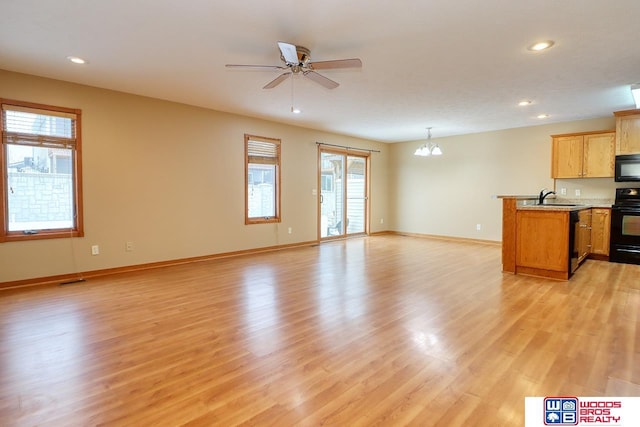 unfurnished living room featuring ceiling fan with notable chandelier, light hardwood / wood-style flooring, and sink