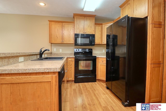 kitchen with sink, black appliances, and light wood-type flooring