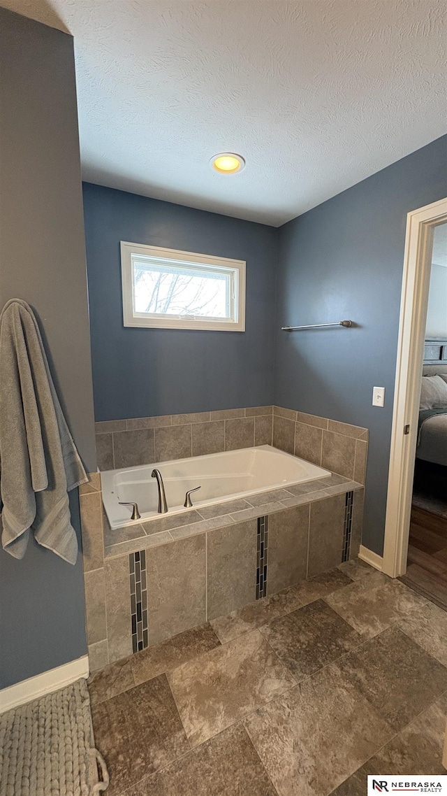 bathroom with a textured ceiling and tiled bath