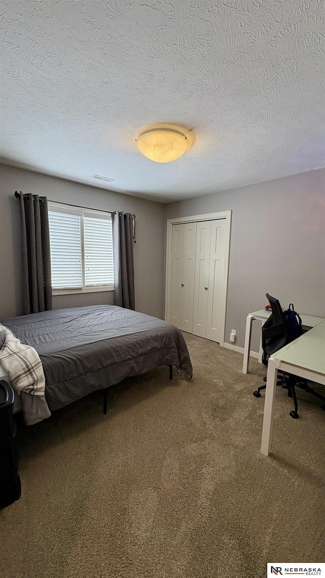 carpeted bedroom featuring a textured ceiling and a closet