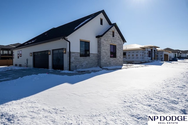 8909 Appaloosa Ln, Lincoln, NE 68520 - snow covered property with stone siding, stucco siding, and a garage