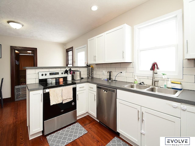 kitchen with appliances with stainless steel finishes, sink, kitchen peninsula, and white cabinets