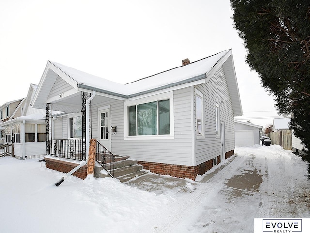 view of front of property featuring a garage, a porch, and an outdoor structure