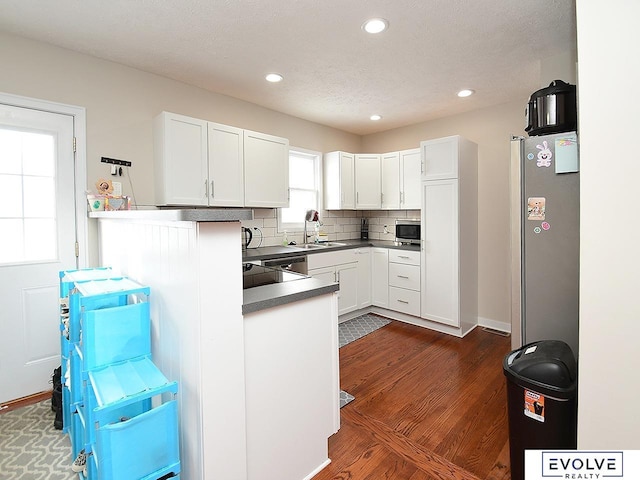 kitchen with sink, white cabinetry, stainless steel appliances, and kitchen peninsula