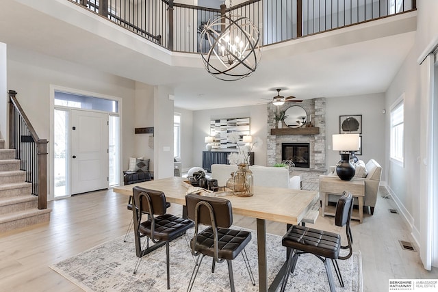 dining room featuring a stone fireplace, a high ceiling, and light hardwood / wood-style floors