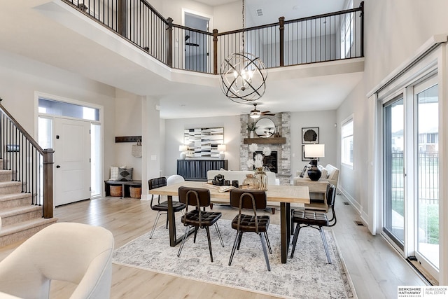 dining area featuring a fireplace, light hardwood / wood-style floors, and a high ceiling