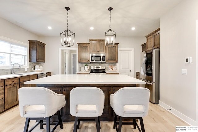 kitchen with sink, stainless steel appliances, pendant lighting, and a center island