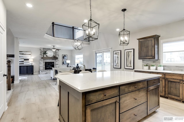 kitchen with a fireplace, a kitchen island, a wealth of natural light, and decorative light fixtures