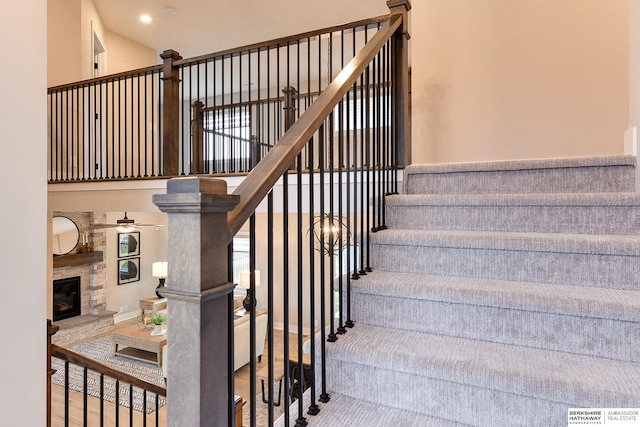 stairs featuring a high ceiling, hardwood / wood-style flooring, and a stone fireplace