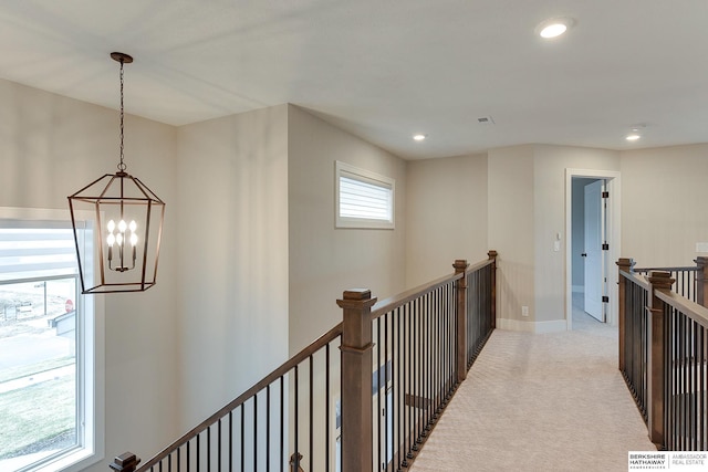 hall with a chandelier and light colored carpet