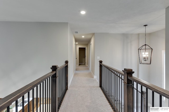 corridor with light carpet and a chandelier