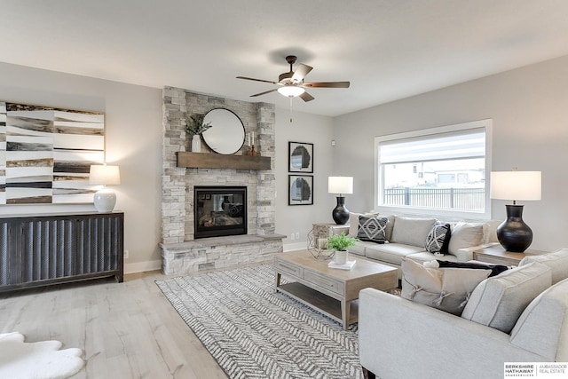 living room featuring light hardwood / wood-style flooring, ceiling fan, and a fireplace