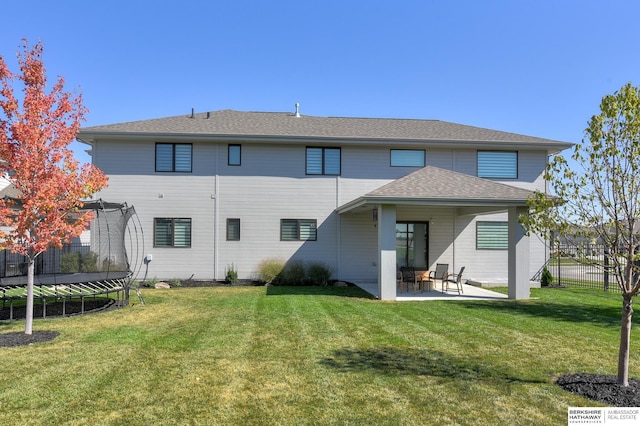 back of house with a trampoline, a lawn, and a patio area