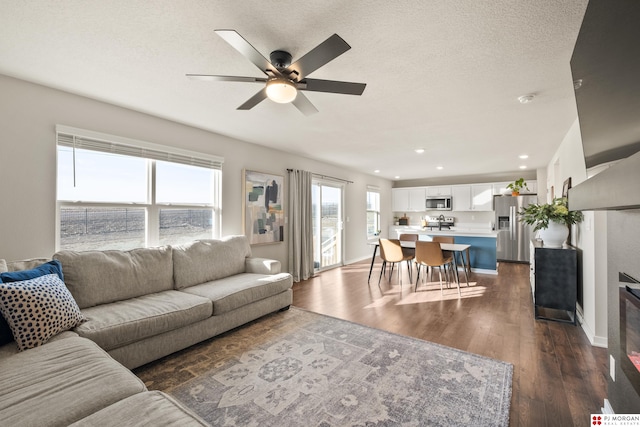 living room featuring a textured ceiling, dark hardwood / wood-style floors, and ceiling fan