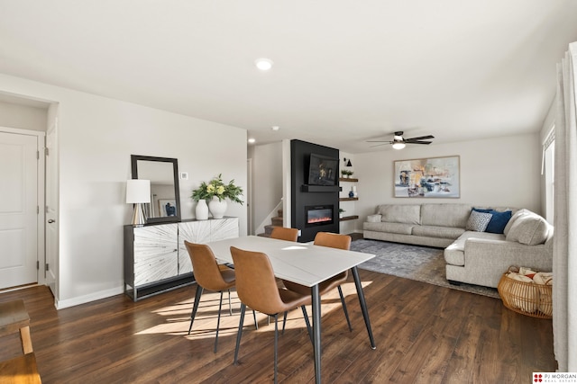 dining room featuring ceiling fan, dark wood-type flooring, and a fireplace