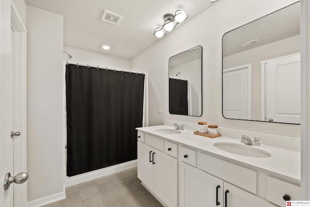 bathroom featuring a textured ceiling, curtained shower, and vanity