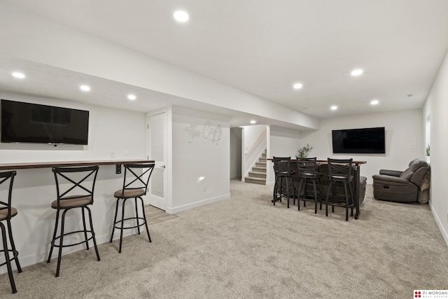 interior space with white cabinets, a kitchen bar, and light colored carpet