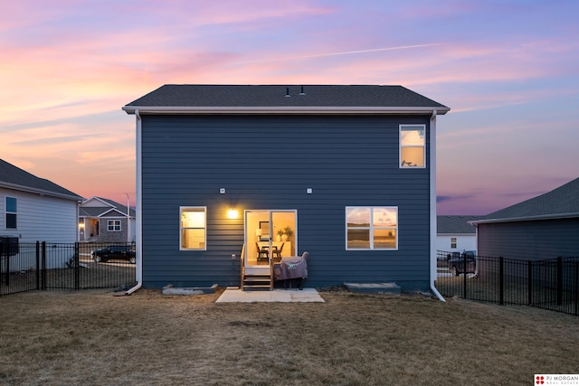 back house at dusk with a lawn